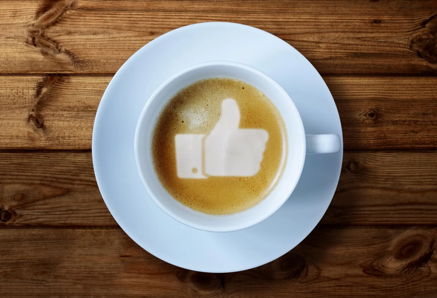 Kaffekopp med et tommel opp-symbol i melkeskummet.