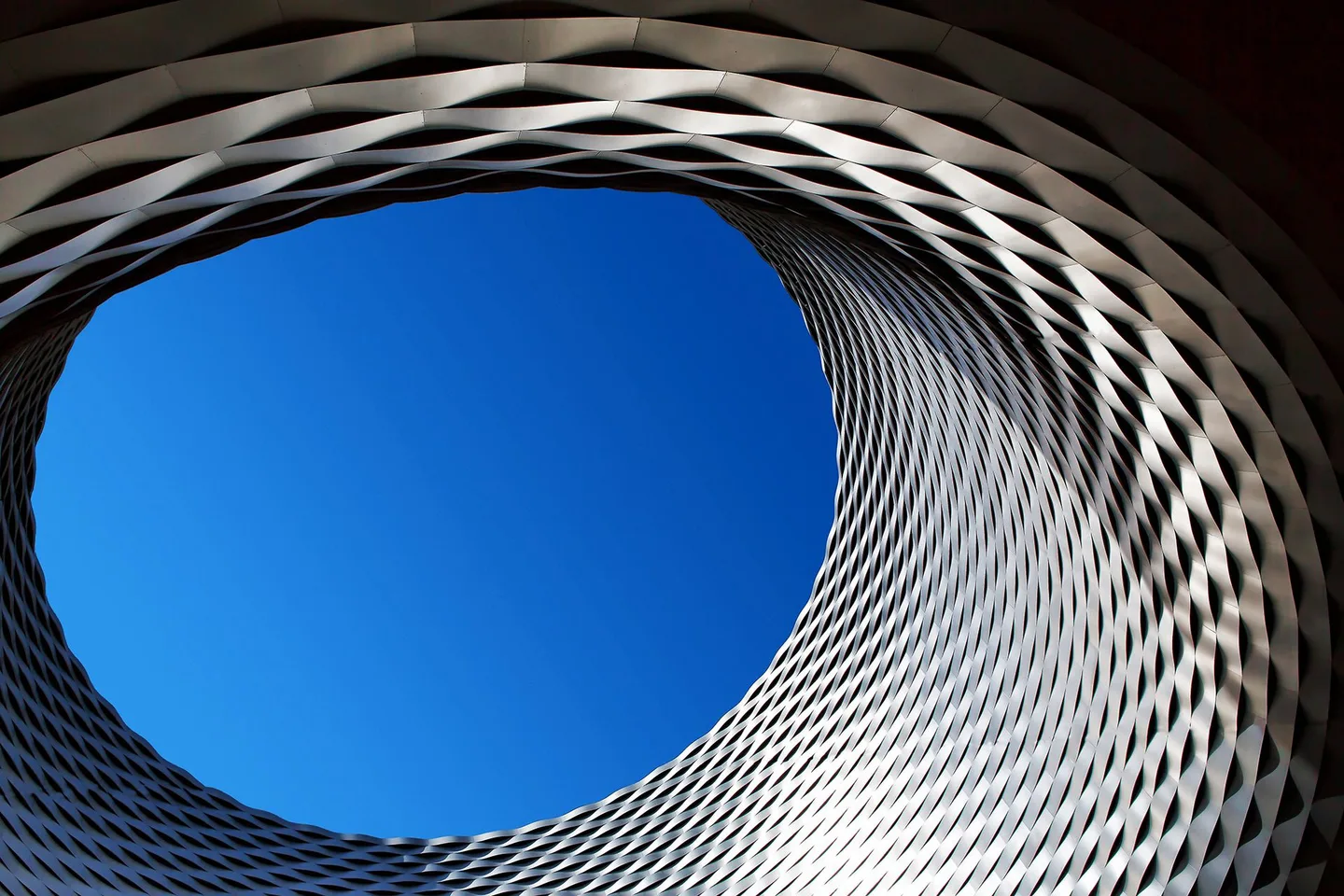 Arkitekturfoto sett nedenfra mot blå himmel.